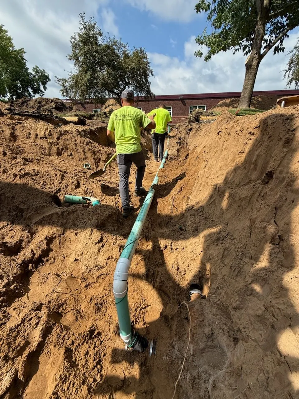 Crew laying sewer line in deep trench